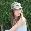 woman-sitting-on-electric-bike-weating-hat-in-front-of-tree-line-closeup